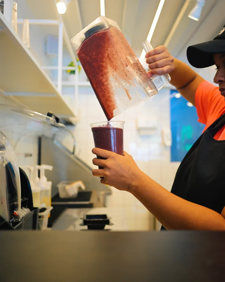 Atendente despejando um smoothie do copo do liquidificador